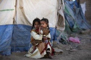 A girl holds her sister outside their tent at a camp for people displaced by recent fighting between government forces and Shi'ite rebels in Saada